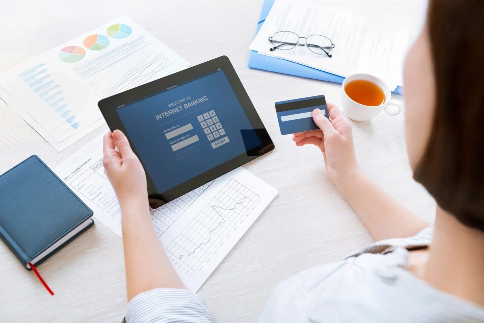 A person holding a credit card and using a tablet.